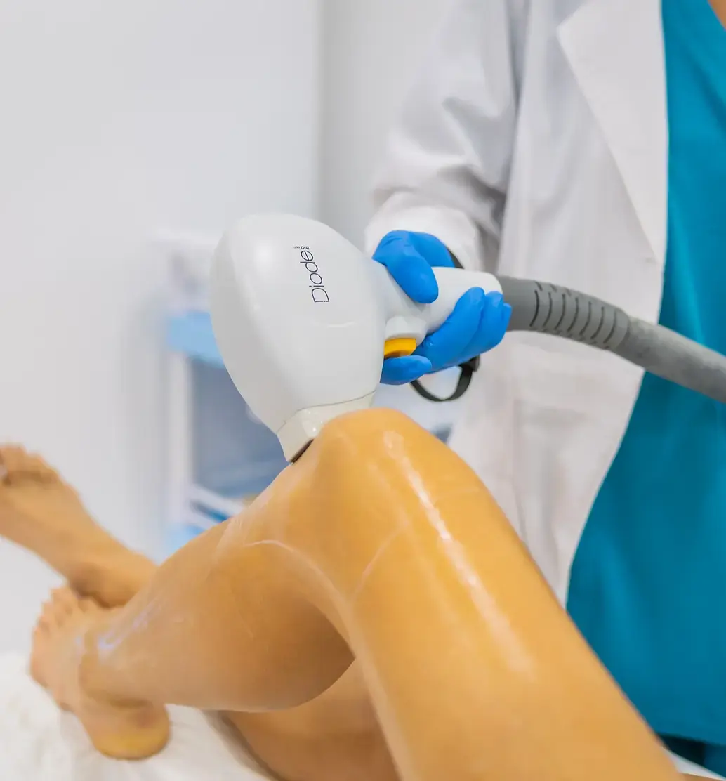 A laser handpiece being passed over a leg covered in clear gel